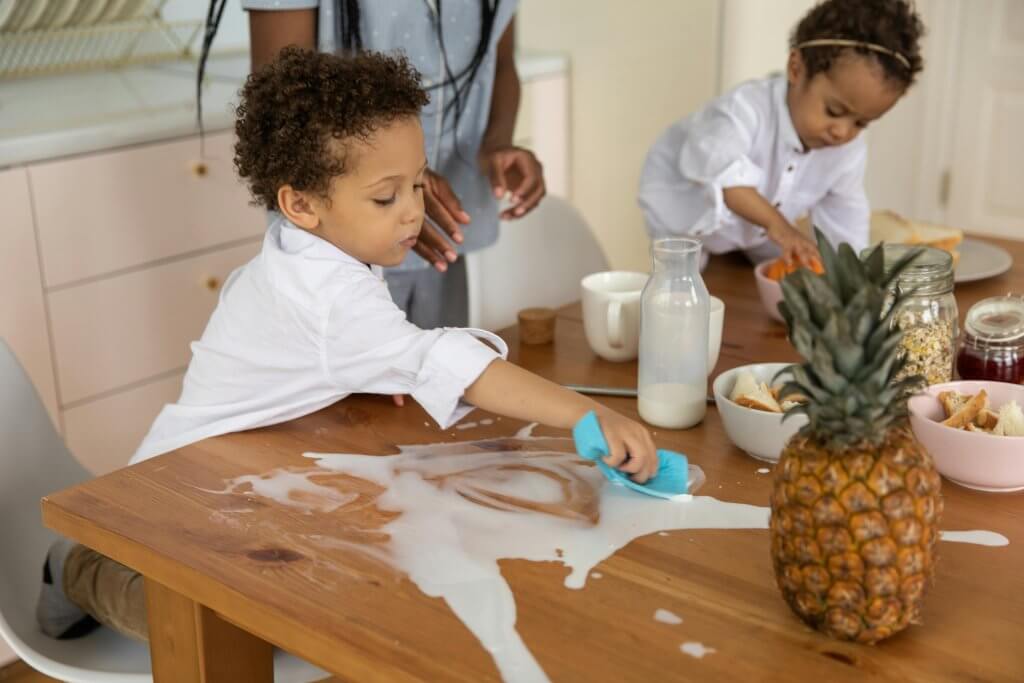 Children cleaning a table with a sponge after playing together and having fun in a sensory play area 